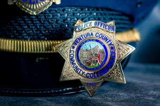Photograph of a VCCCD Police Department badge sitting in front of a Class A cover hat.