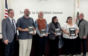Photo of Chancellor MacLennan, Board Chair Perez, and Classified Employee of the Year Honorees holding plaques: Brian Dederian, Kristen Robinson, Erika Hurtado, and Fidelia Flores