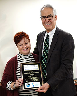 Dena Stevens smiling and holding award