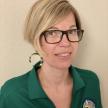 photo of Ariane Perez wearing green Oxnard College polo shirt and standing against cream colored wall