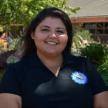 Woman posing outdoors in an Oxnard College polo shirt. 