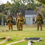 Four Fire Academy students standing outdoors in uniforms wit