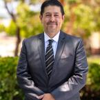 Dr. Roberto Gonzalez standing outside wearing a suit and smi