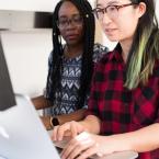 Two women sharing a computer screen.