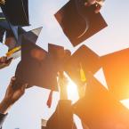 College graduates holding their caps and tassels in the air. 