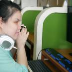 Visually impaired woman using a screen reader and head phones at a computer.