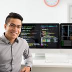 Male student is sitting at a computer with two large monitors