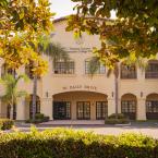 Image: District Administrative Building framed by trees to the left and right and bushes along the bottom