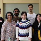 Image: Woman, Claudia Wilroy, smiling and standing with five International students at a student luncheon
