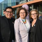 Ventura College President Claudia Lourido-Habib, center, stands smiling between event emcees Oscar Rivera, left, and Brook Masters, right, in front of the Applied Science Center at Ventura College during the 2025 Lavender Graduation. The group is outdoors on a sunny day, surrounded by attendees celebrating LGBTQIA+ graduates.