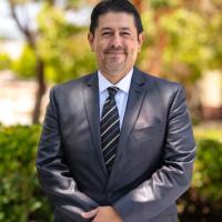 Dr. Roberto Gonzalez standing outside wearing a suit and smi