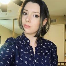 Allie Frazier, a woman with a brunette bob wearing a blue floral button down shirt in front of a beige background