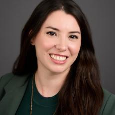 Allie Frazier, feminine person with long, wavy hair wearing a blazer
