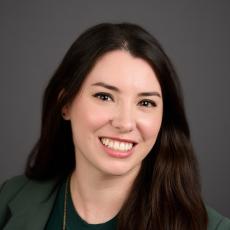 Allie Frazier, feminine person with long, wavy, dark hair wearing a green blazer and green shirt