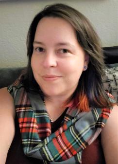 woman looks directly at the camera, red and green scarf around her neck