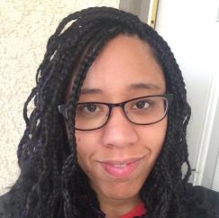 picture of a black haired woman with braids smiling at the camera