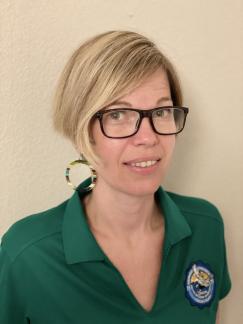 photo of Ariane Perez wearing green Oxnard College polo shirt and standing against cream colored wall