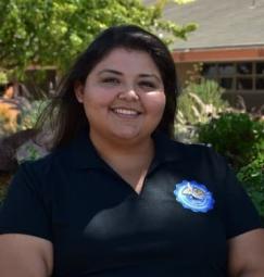 Woman posing outdoors in an Oxnard College polo shirt. 