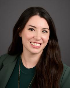 Allie Frazier, feminine person with long, wavy, dark hair wearing a green blazer and green shirt