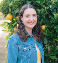 Headshot of Cristy, who has shoulder length curly brown hair and is wearing a jean jacket
