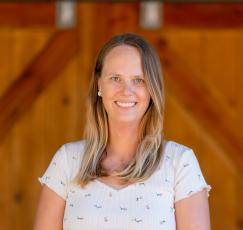 Blonde woman smiling and standing in front of barn doors
