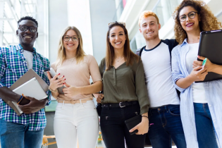 group of five students of different ethnicities and genders standing in a semicircle and smiling