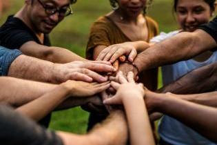 Several students' hands gathered together to display teamwork