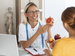 Female Nutritionist demonstrating a orange to a client 