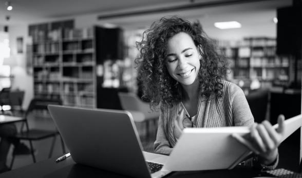 Young adult college student studying with a textbook and a l