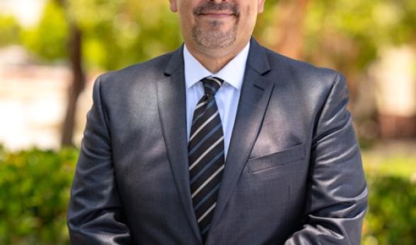 Dr. Roberto Gonzalez standing outside wearing a suit and smi