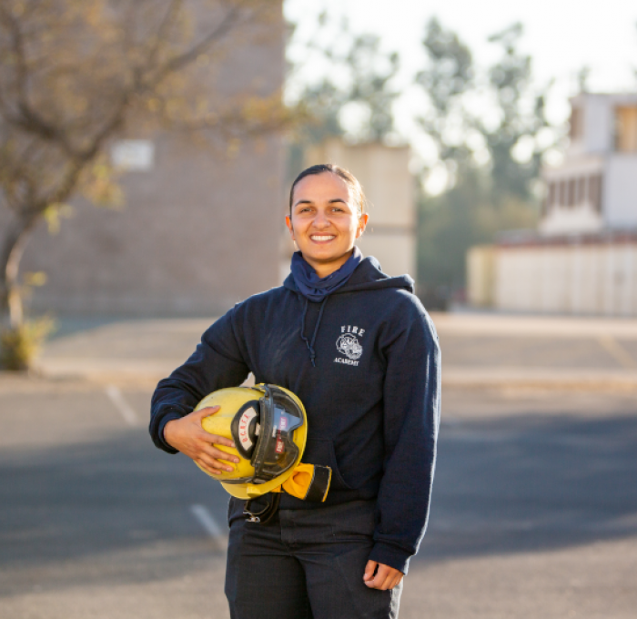Female Fire Academy Student Holding Firefighter's Helmet