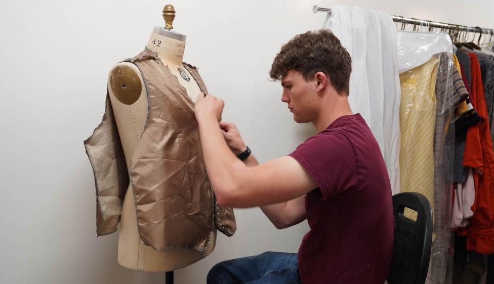 Moorpark College Costuming Student working on a vest on a dress mannequin.