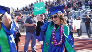 Oxnard College graduate holding a sign that reads: OC Transf Oxnard College graduate holding a sign that reads: OC Transf