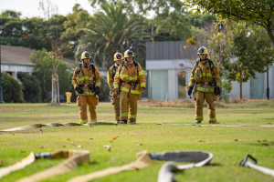 Four Fire Academy students standing outdoors in uniforms wit Four Fire Academy students standing outdoors in uniforms wit