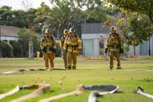 Four Fire Academy students standing outdoors in uniforms wit