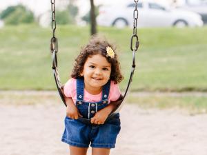 Little girl leaning on a swing at an outdoor park. Little girl leaning on a swing at an outdoor park.