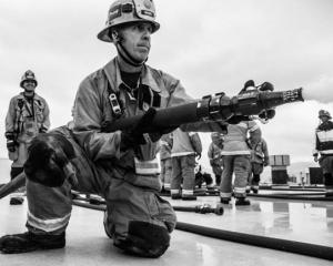 Jack Twitchell in full firefighter garb with a fire hose. 