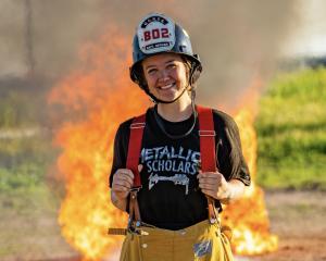 A young woman wearing a firefighter’s helmet and yellow pant A young woman wearing a firefighter’s helmet and yellow pant
