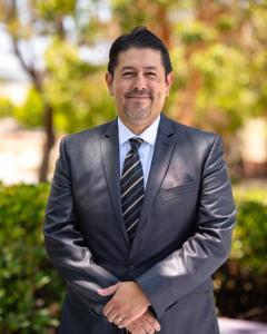Dr. Roberto Gonzalez standing outside wearing a suit and smi