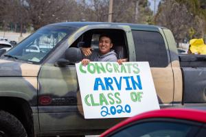 Drive thru graduation at Oxnard College, student holding a sign saying "Congrats Arvin Class of 2020"