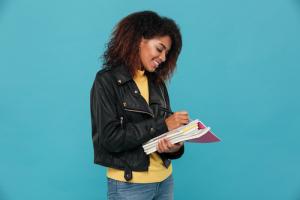 African American woman smiling while highlighting in a textbook.