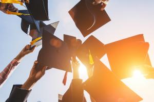 College graduates holding their caps and tassels in the air. 