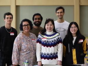 Image: Woman, Claudia Wilroy, smiling and standing with five International students at a student luncheon